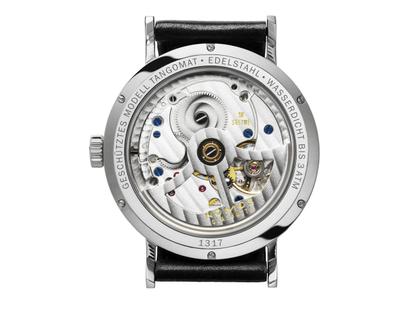Nomos Glashütte Tangomat Automatik Edelstahl 38mm weißes Zifferblatt schwarzes Lederband Glasboden – Herrenuhren Uhr ohne Datum aus Edelstahl und Leder. Das Gehäuse ist rund und silber. Das Lederarmband ist schwarz. Das Zifferblatt ist arabisch Index und weiß. – Ansicht 2