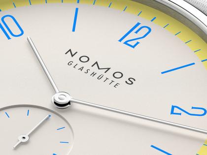Nomos Glashütte Tangente 38 Datum "175 Years Watchmaking - Lemonbiscuit" Handaufzug Edelstahl cremeweißes Zifferblatt graues Textilband Glasboden – Herrenuhren Uhr mit Datum aus Edelstahl. Das Gehäuse ist rund und silber. Das Textilarmband ist grau. Das Zifferblatt ist arabisch Index und beige. – Ansicht 6