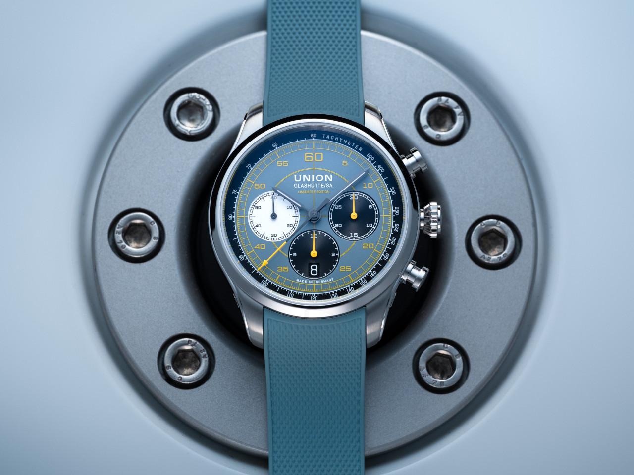 Union Glashütte Belisar Chronograph Speedster 2025 Limited Edition Automatik Edelstahl 44mm blaues Zifferblatt blaues Kautschukband – Herrenuhren Chronograph aus Edelstahl und Kautschuk. Das Gehäuse ist rund und silber. Das Kautschuk / Kunststoff / Silikon Armband ist blau. Das Zifferblatt ist arabisch und blau. – Ansicht 6