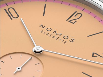 Nomos Glashütte Tangente 38 Datum "175 Years Watchmaking - Pastell" Handaufzug Edelstahl korallfarbenes Zifferblatt graues Textilband Glasboden – Herrenuhren Uhr mit Datum aus Edelstahl. Das Gehäuse ist rund und silber. Das Textilarmband ist grau. Das Zifferblatt ist arabisch Index und orange. – Ansicht 5