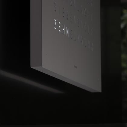 Qlocktwo Earth 45 Grey Pepper Monochrome Edition – Großuhren Wanduhr aus . Das Gehäuse ist quadratisch und weiß. Das Zifferblatt ist digital und grau. – Ansicht 3