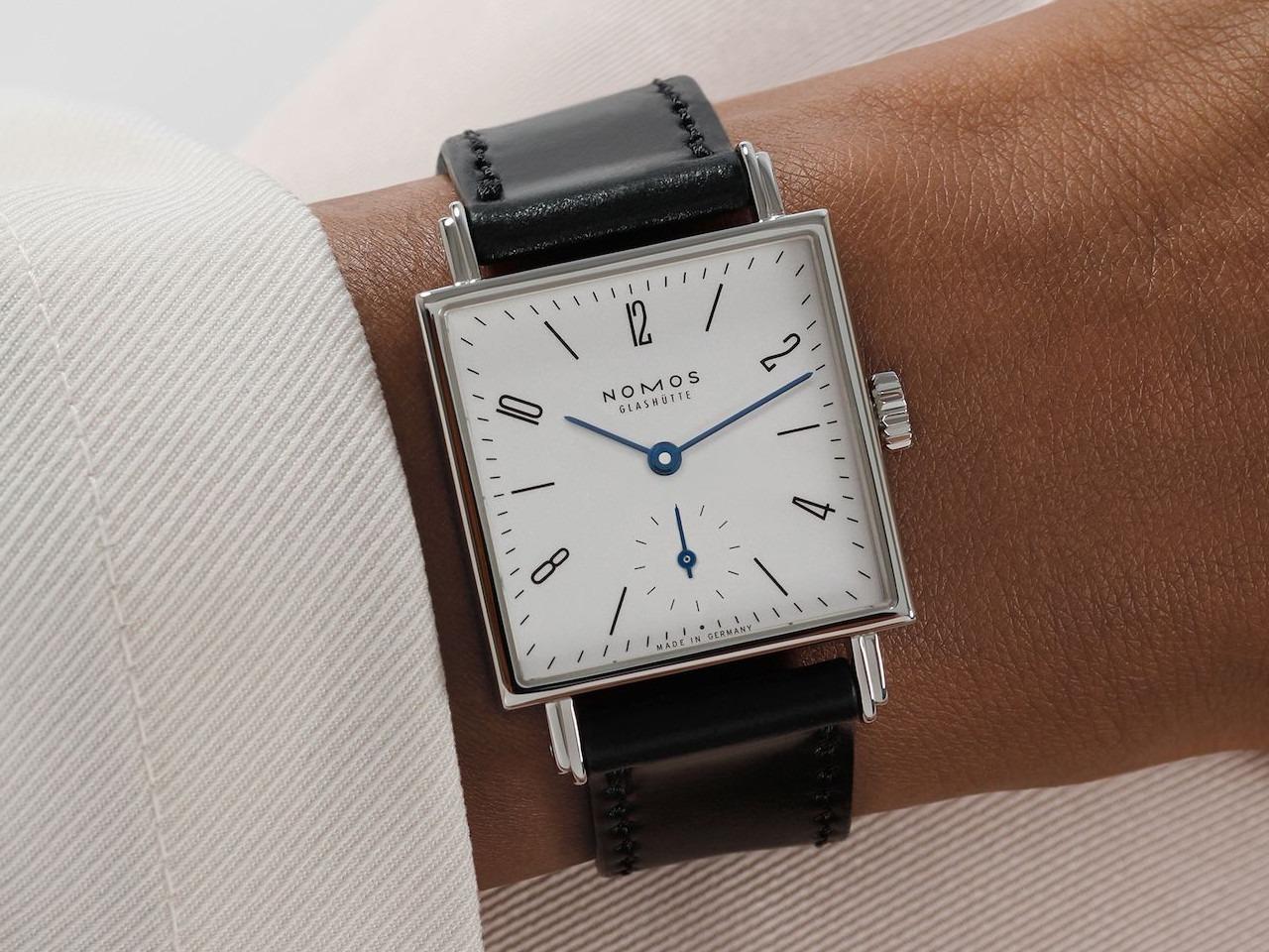 Nomos Glashütte Tetra 27 Weiss Handaufzug Edelstahl 27mm weißes Zifferblatt schwarzes Lederband Glasboden – Damenuhren Uhr ohne Datum aus Edelstahl und Leder. Das Gehäuse ist quadratisch und silber. Das Lederarmband ist schwarz. Das Zifferblatt ist arabisch Index und weiß. – Ansicht 9