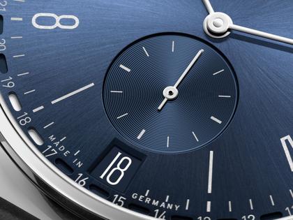 Nomos Glashütte Tangente 2date Handaufzug Edelstahl 38mm blaues Zifferblatt schwarzes Lederband Glasboden – Herrenuhren Uhr mit Datum aus Edelstahl und Leder. Das Gehäuse ist rund und silber. Das Lederarmband ist schwarz. Das Zifferblatt ist arabisch Index und blau. – Ansicht 8