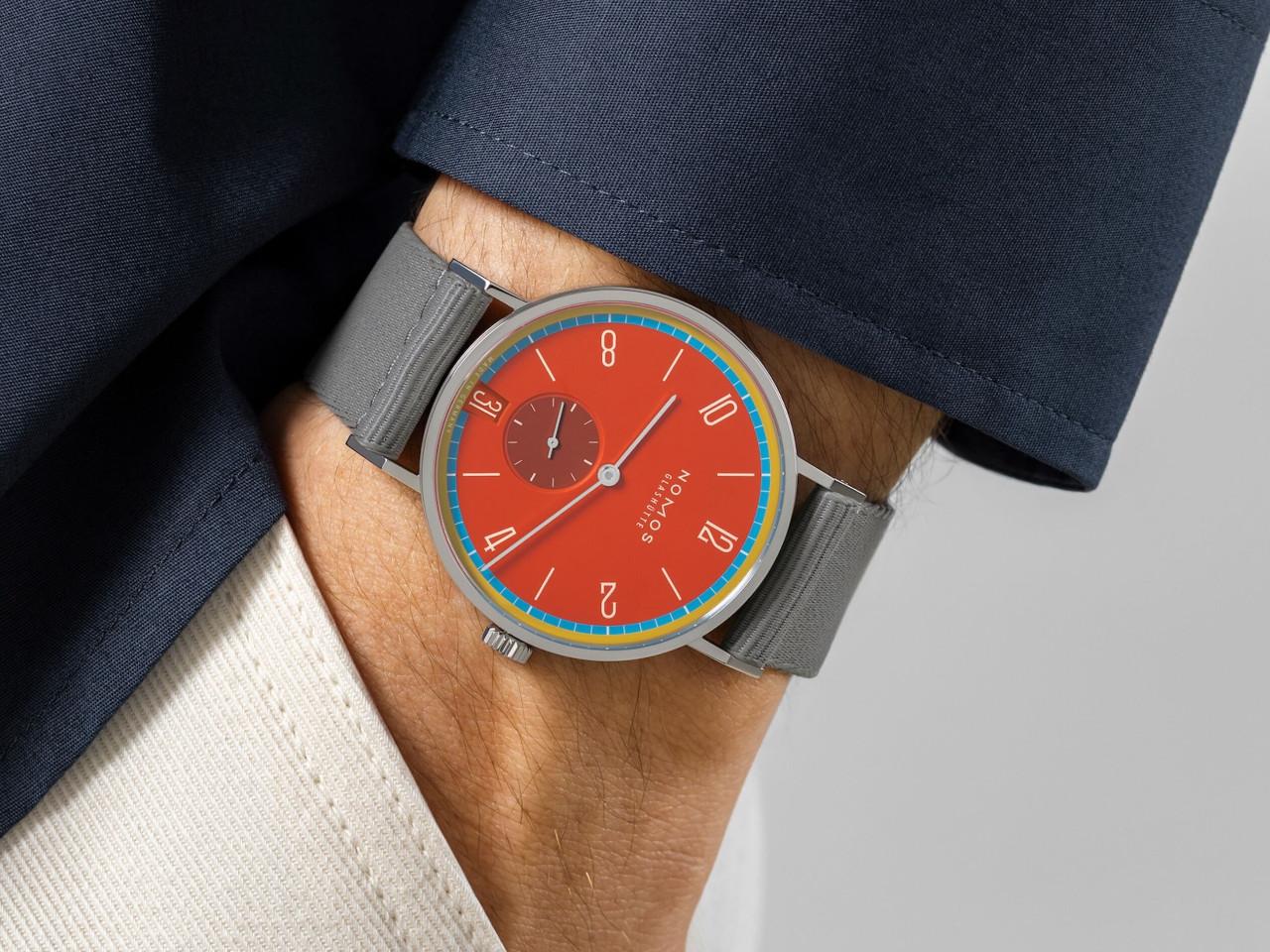 Nomos Glashütte Tangente 38 Datum "175 Years Watchmaking - Sportbunt" Handaufzug Edelstahl rotes Zifferblatt graues Textilband Glasboden – Herrenuhren Uhr mit Datum aus Edelstahl. Das Gehäuse ist rund und silber. Das Textilarmband ist grau. Das Zifferblatt ist arabisch Index und rot. – Ansicht 7