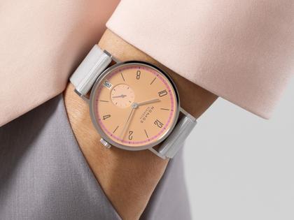 Nomos Glashütte Tangente 38 Datum "175 Years Watchmaking - Pastell" Handaufzug Edelstahl korallfarbenes Zifferblatt graues Textilband Glasboden – Herrenuhren Uhr mit Datum aus Edelstahl. Das Gehäuse ist rund und silber. Das Textilarmband ist grau. Das Zifferblatt ist arabisch Index und orange. – Ansicht 7